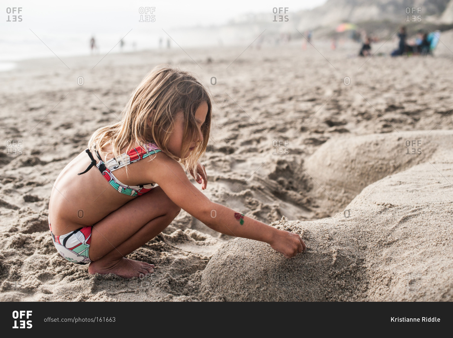 A little girl makes a sand sculpture