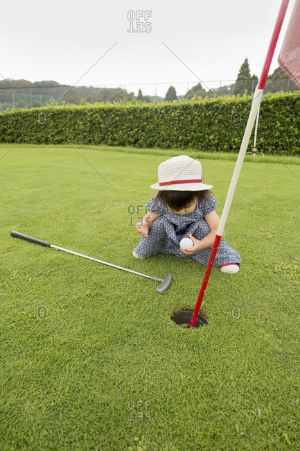 Young girl sitting by a golf course hole