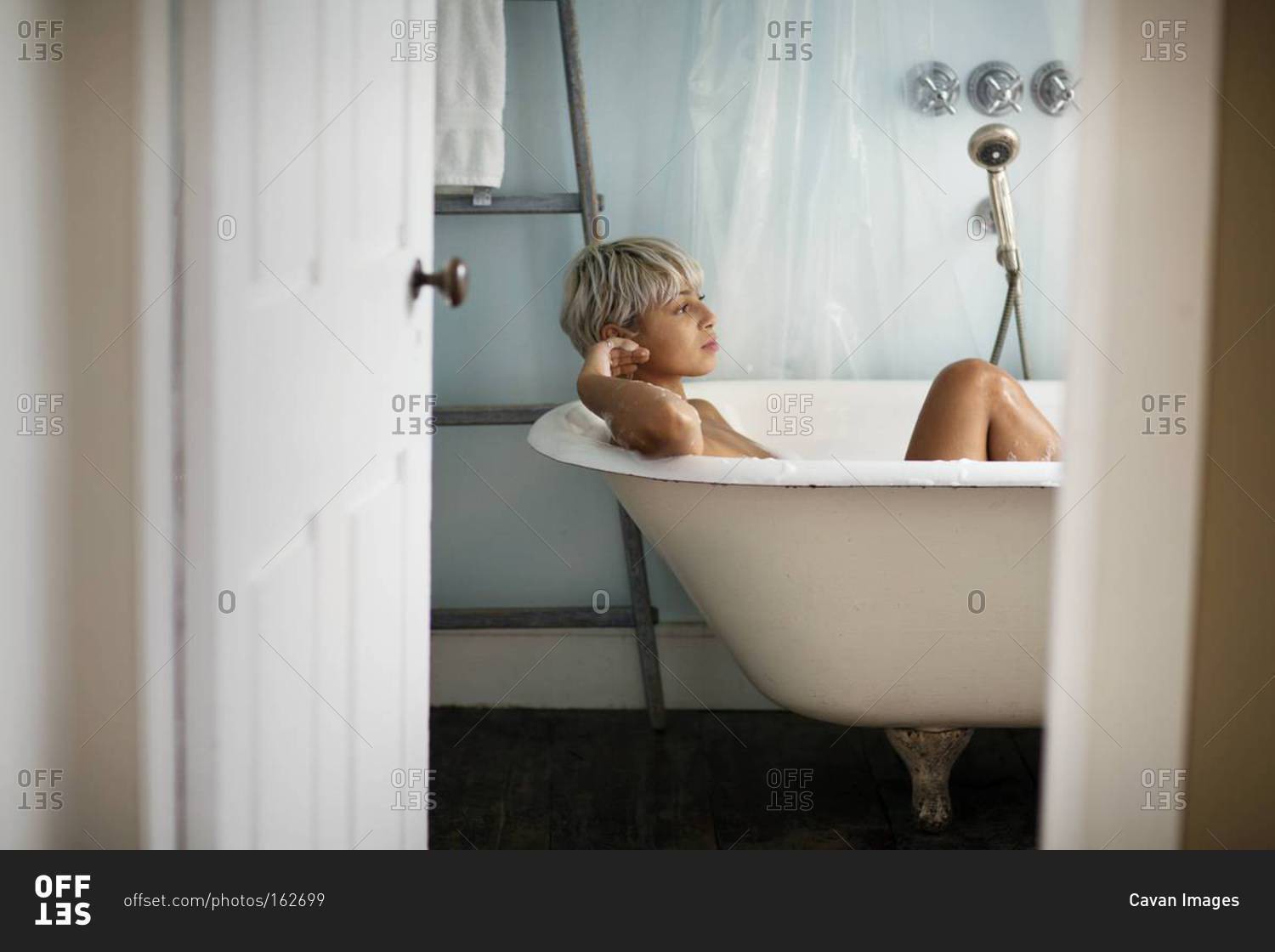 Woman taking a bath in bath tub at home stock photo - OFFSET
