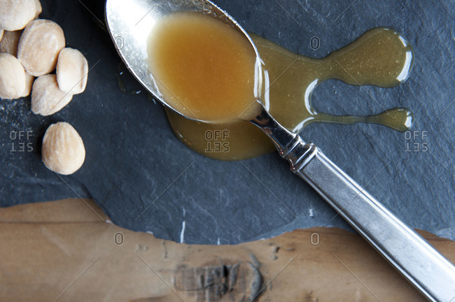Overhead view of a spoonful of honey and marcona almonds resting on slate