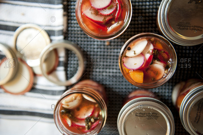 Overhead of jars carrots and radishes being pickled