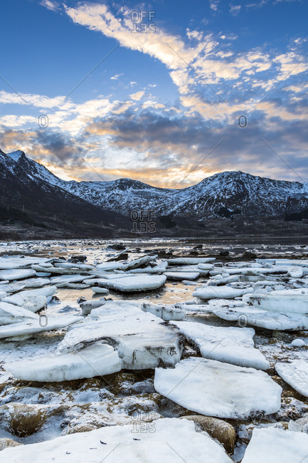Ice and rocks in a sundown at the coastline of Gimsoy, Lofoten, Norway