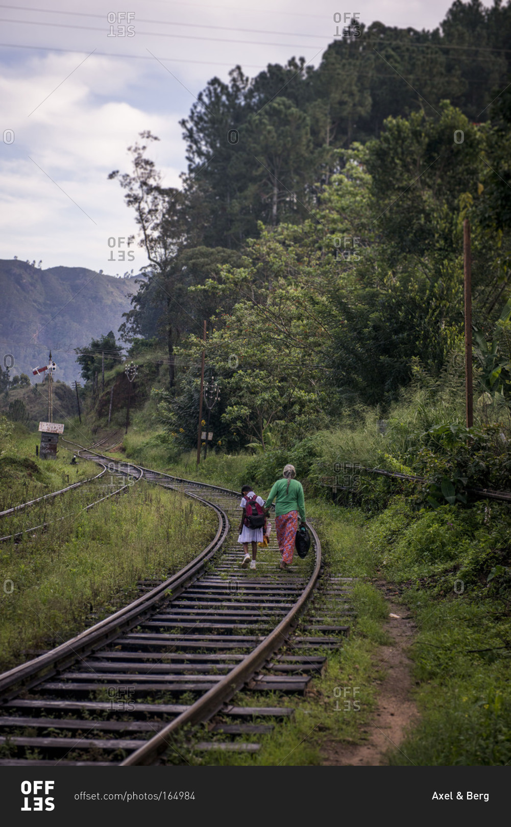 Back view of woman and child walking on train tracks