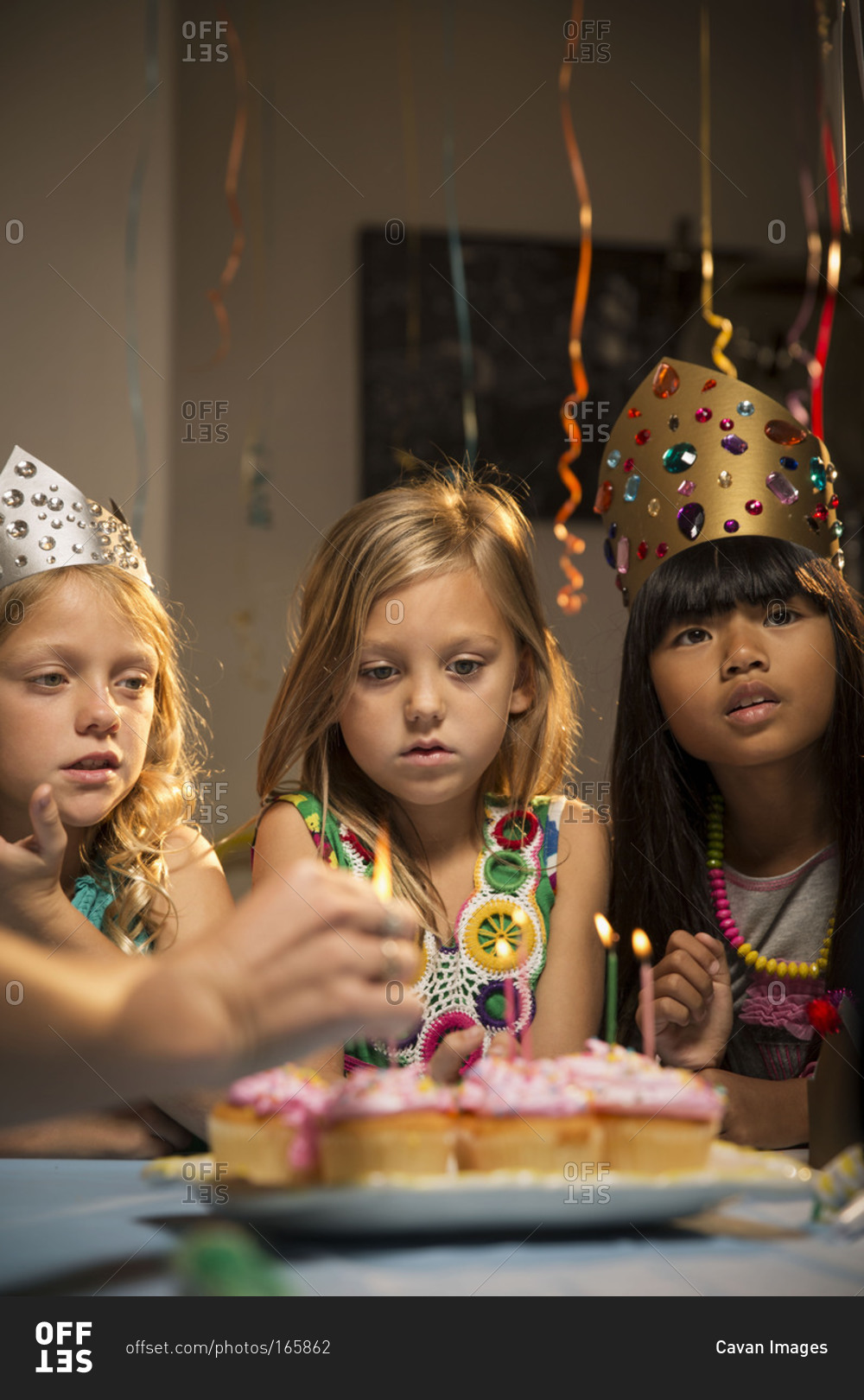 Three girls watch candles being lighted at party