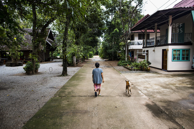 A woman at Wat Pa Suthawas walking through the temple grounds with a dog at her side, in Sakon Nakhon province, northeastern Thailand