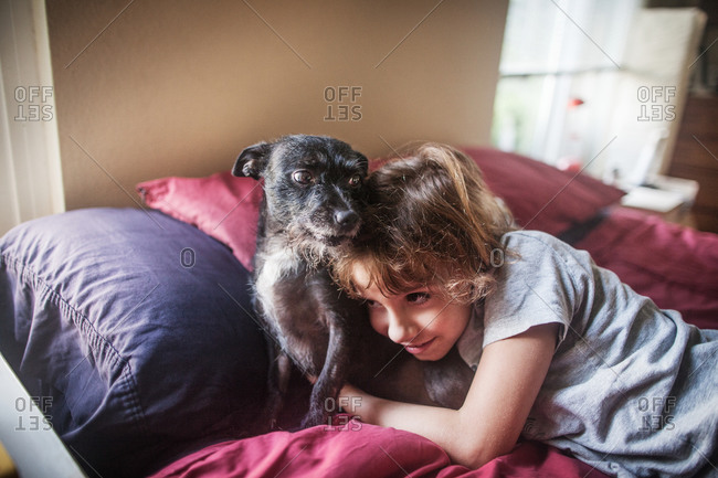 Boy and dog cuddling on bed