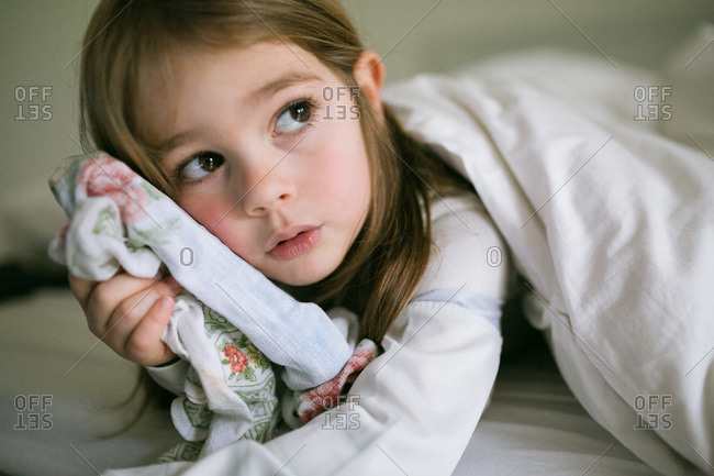 A little girl cuddles her blanket