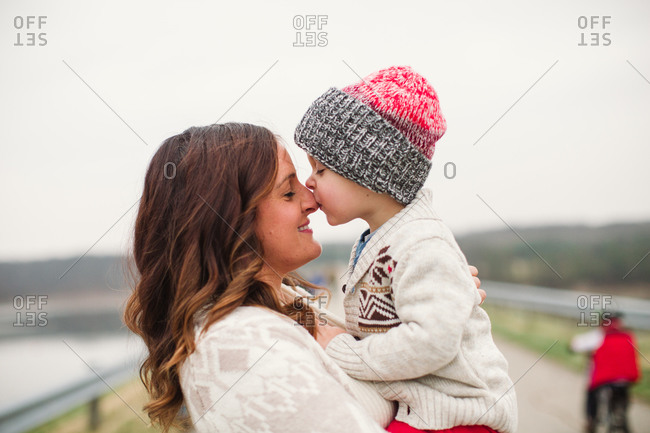 Toddler son kissing his mother on her nose