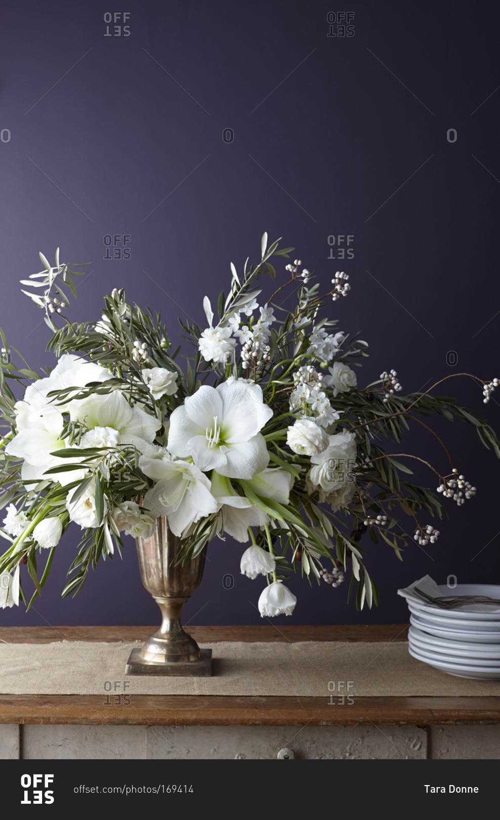 White bouquet of flowers in a copper vase and plates Stock Image