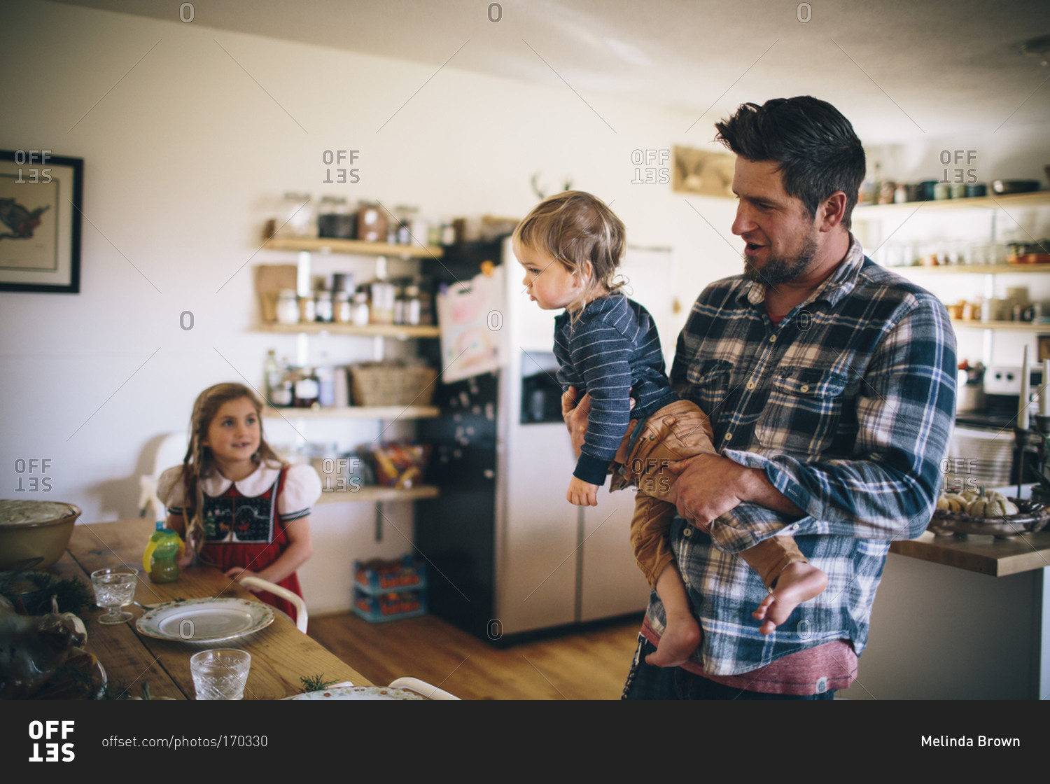 A dad brings his baby to the dining table for Christmas dinner