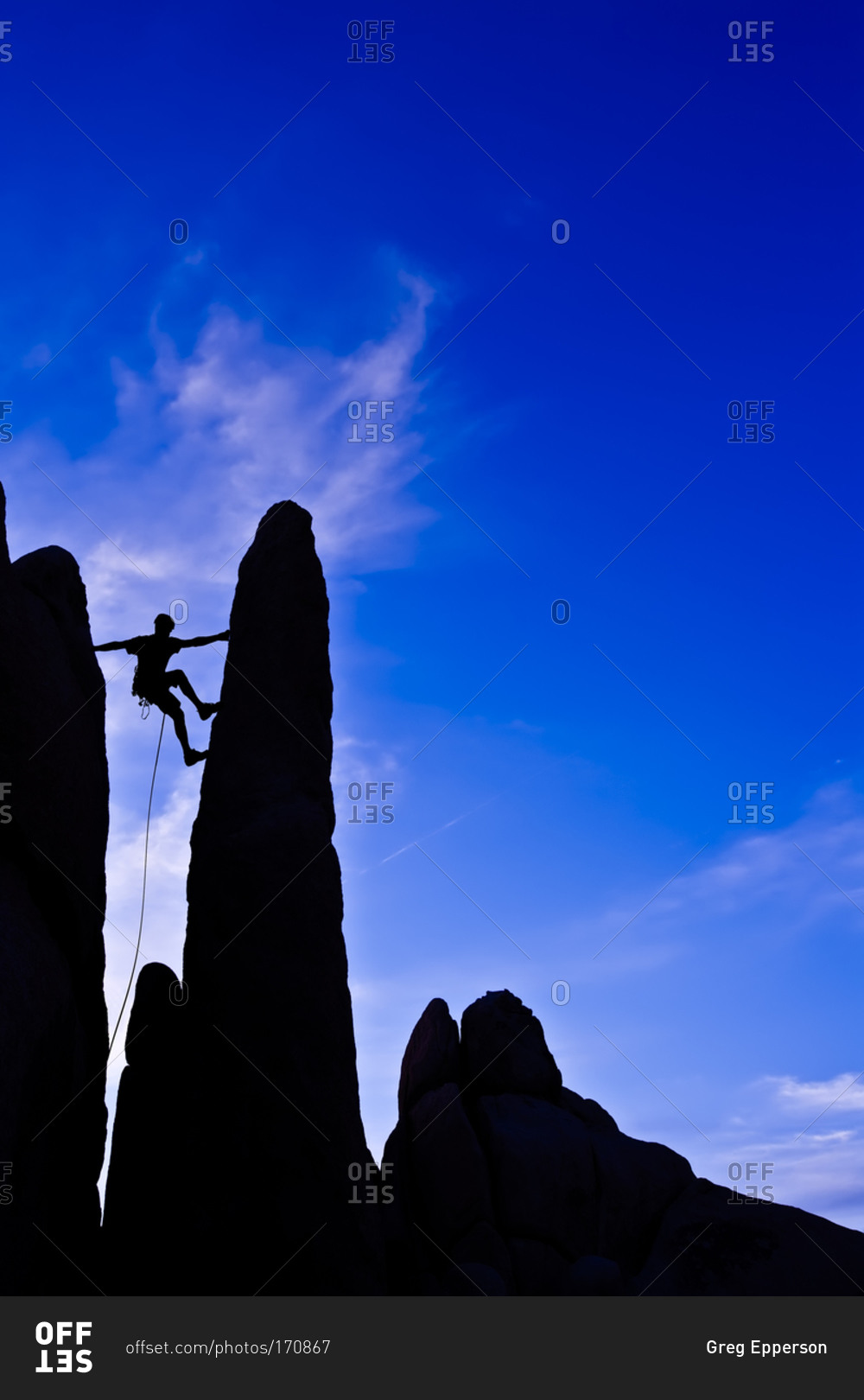 Silhouette of man climbing up a rock formation