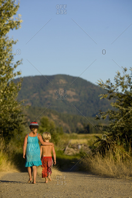 Boy and girl rolling down hill stock photo - OFFSET