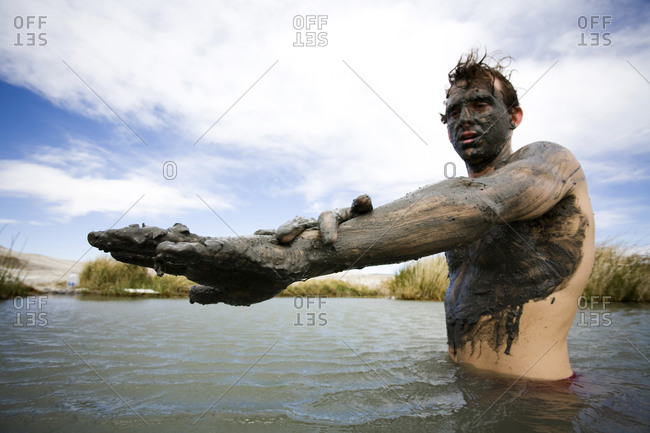 A man, covered in mud, baths in a hot springs, Tecopa, California, USA ...