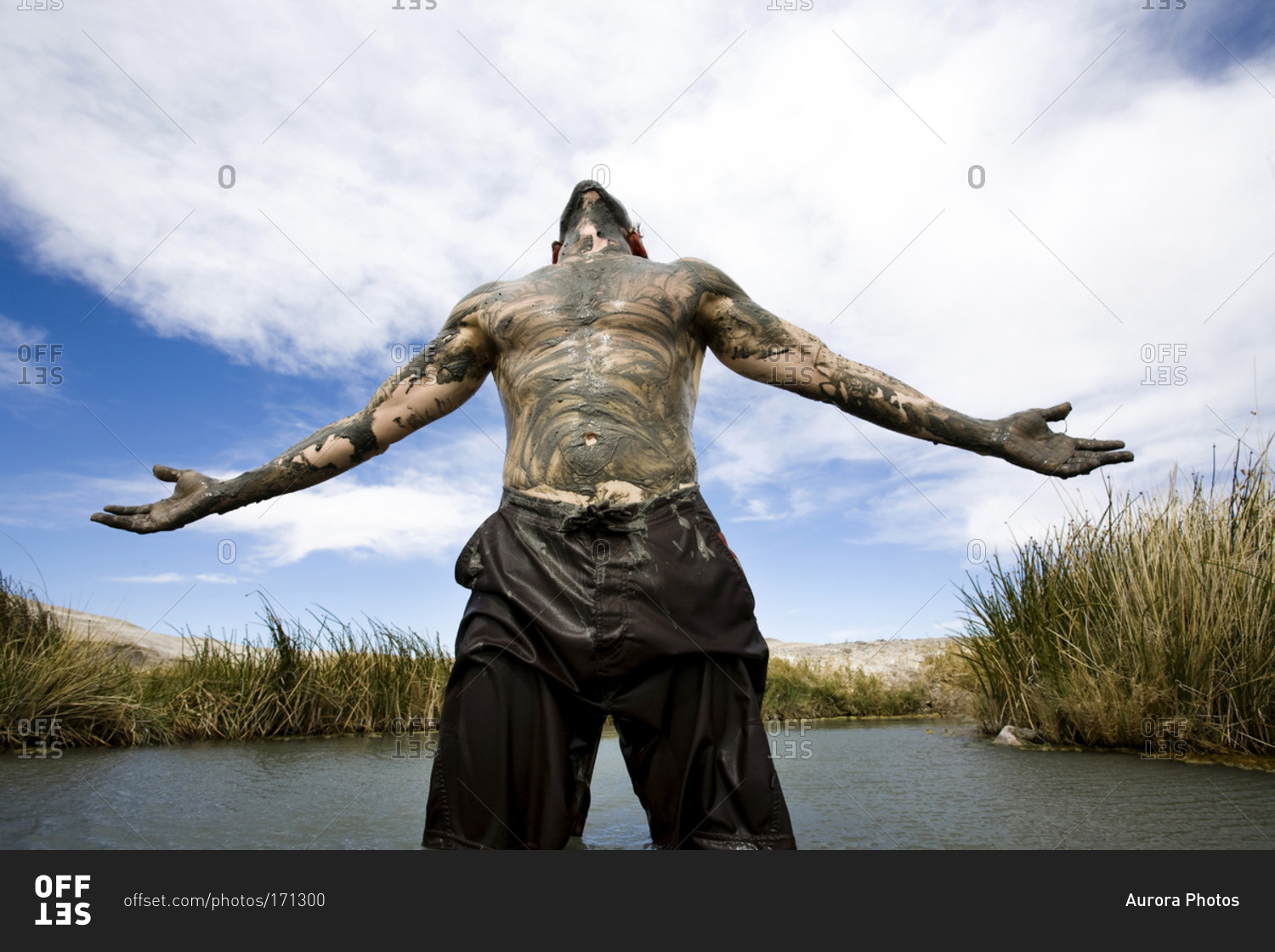 A Man Stands Shirtless And Covered In Mud In A Hot Springs With Arms Out To His Side Tecopa