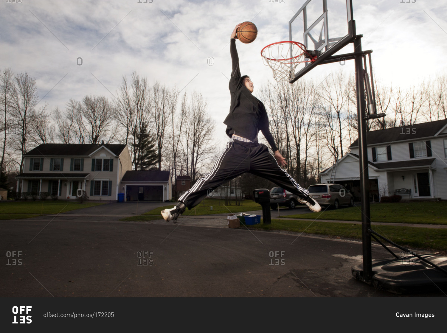 Teenager dunking a basketball into the hoop stock photo OFFSET