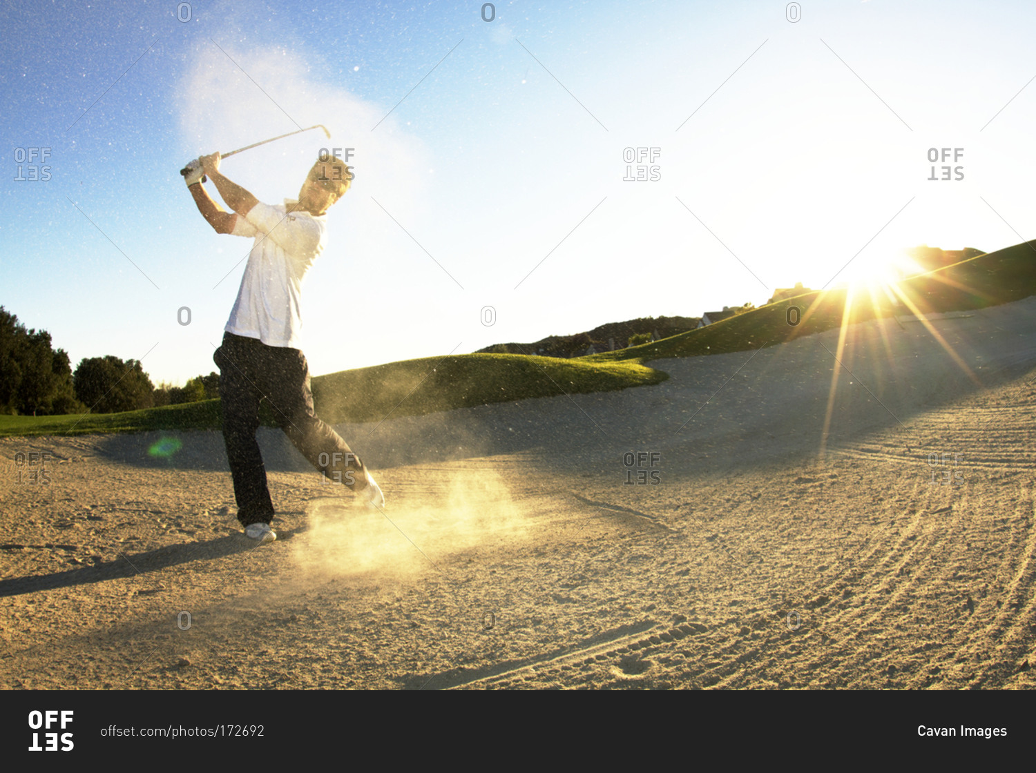 A man hitting golf ball out of sand trap