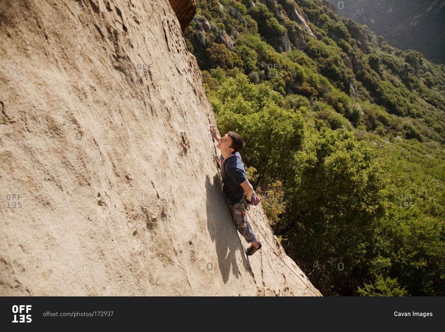 Man looks to top of mountain he is climbing