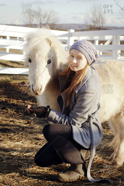 Young girl with arm around miniature pony