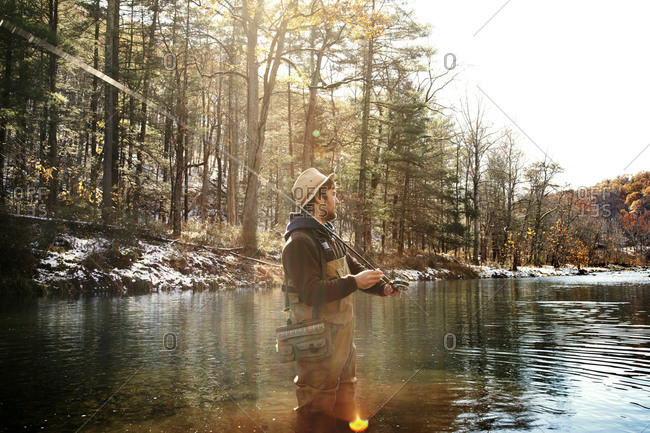 Young man fly fishing in winter