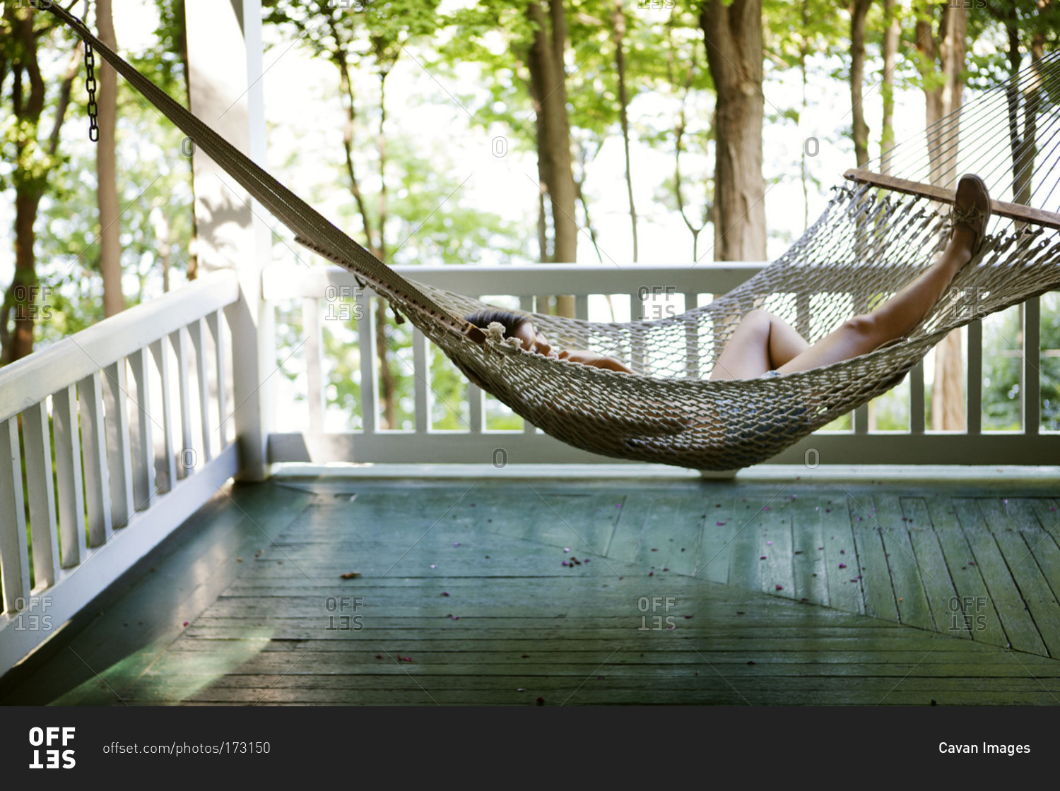 Young woman relaxing on porch hammock stock photo OFFSET