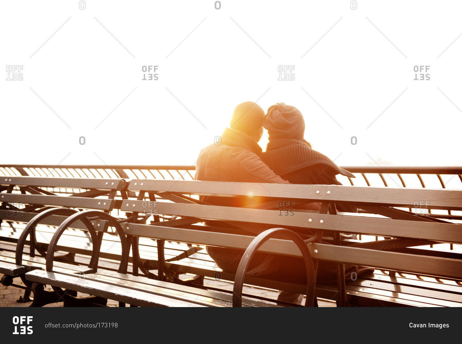 Young couple sitting on bench watching sunset