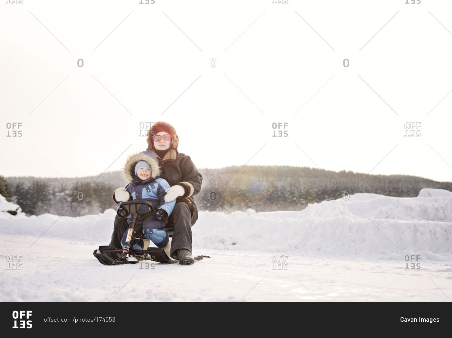 Mom and son sitting on mini snowmobile