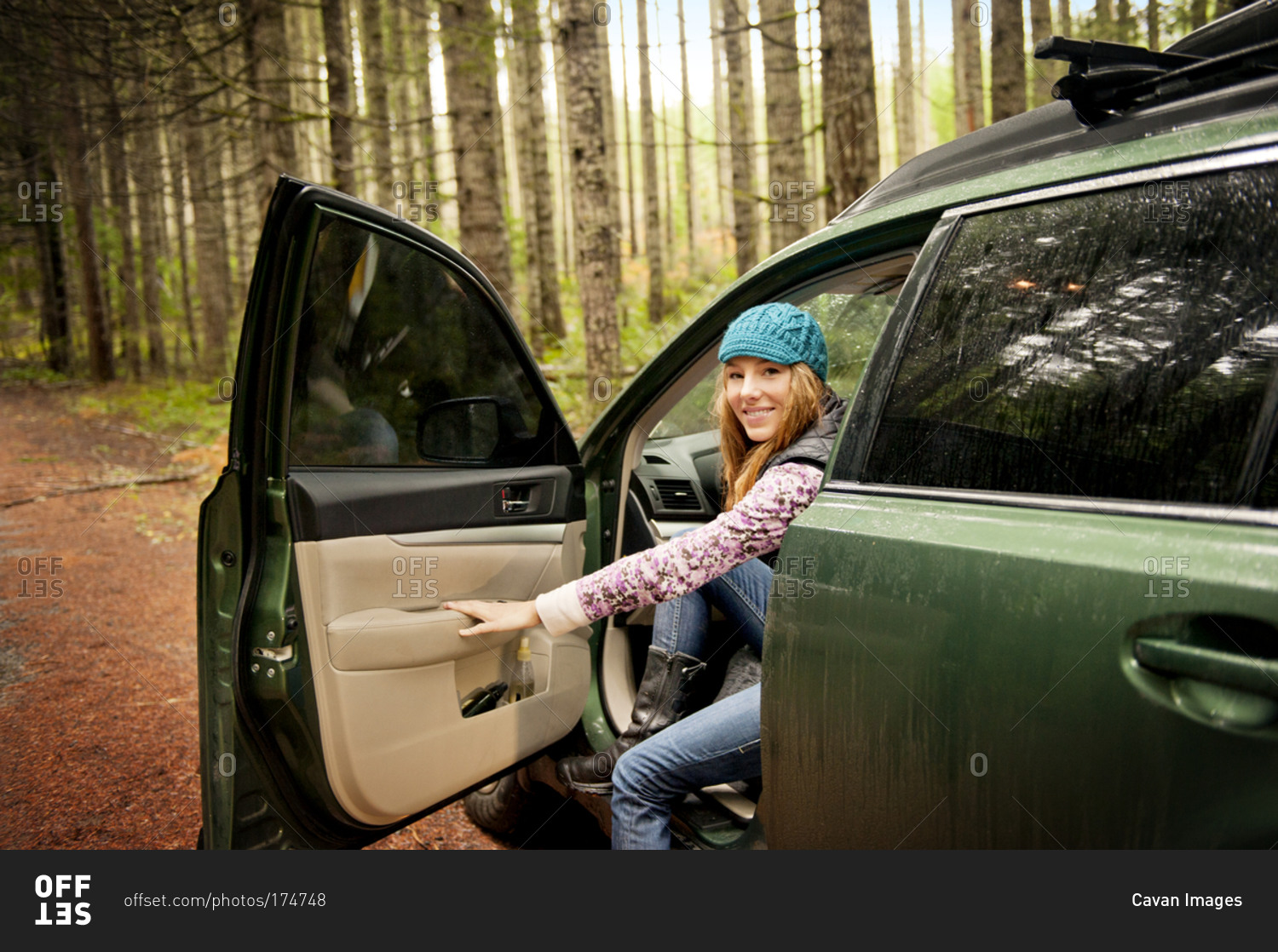 A woman getting out of her car in the woods