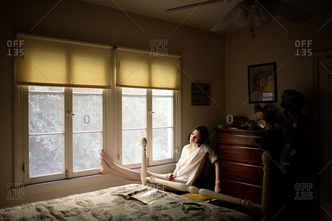 Young woman sitting alone in bedroom