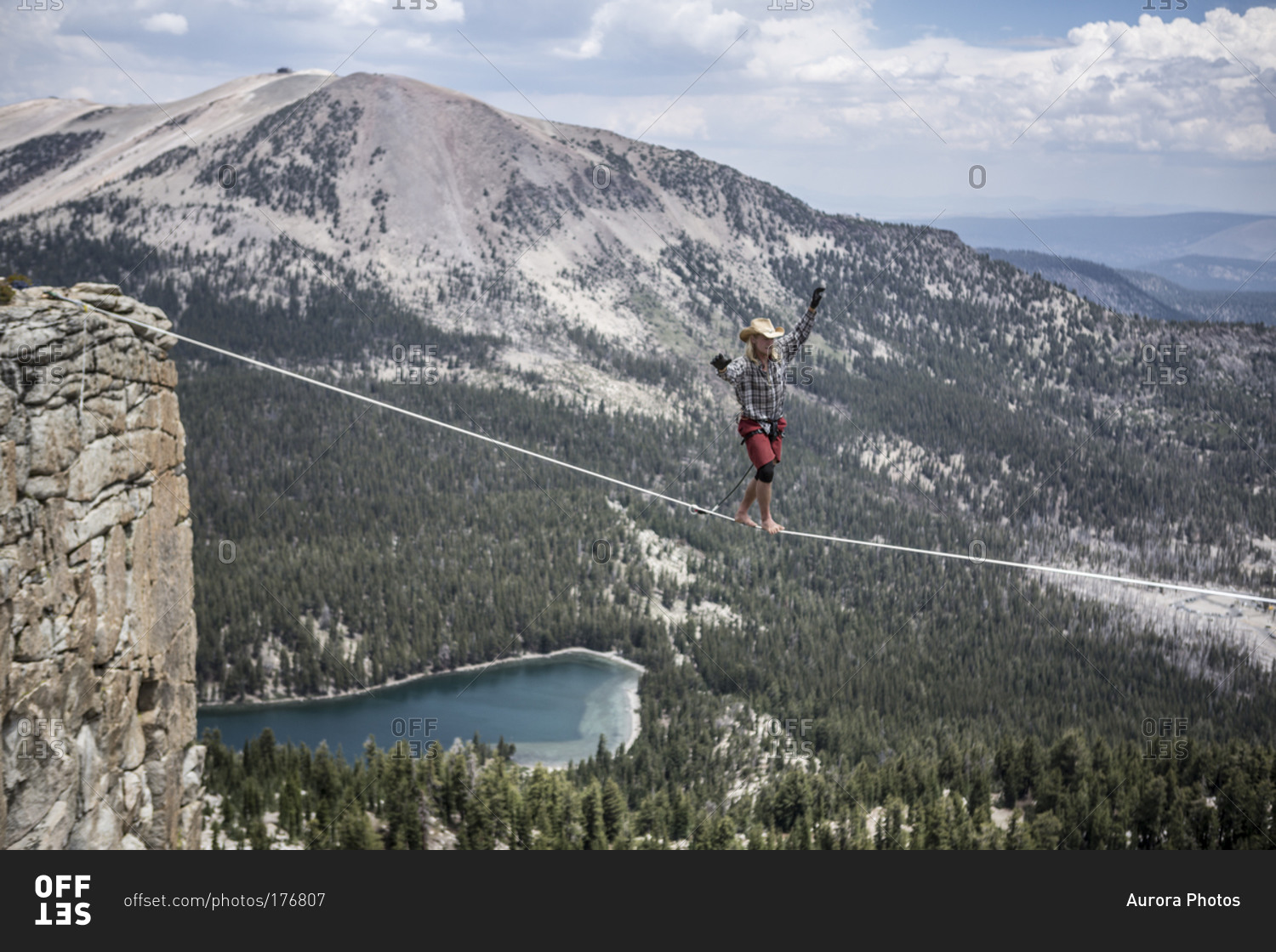 Male highliner in cowboy hat walks a 125 foot highline over a lake in a gap on top of Mammoth Crest