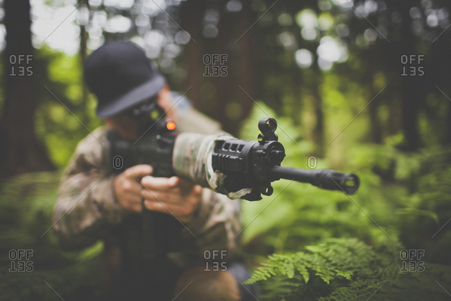A soldier takes aim, his automatic weapon