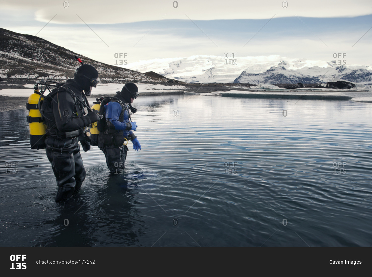 Two scuba divers walk into the water in Iceland