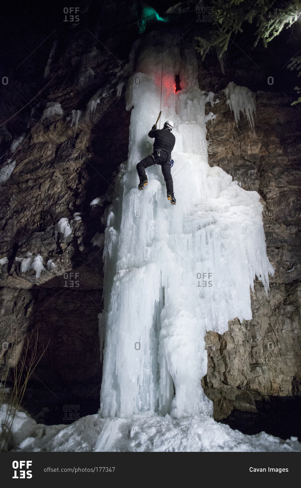 A man ice climbing at night