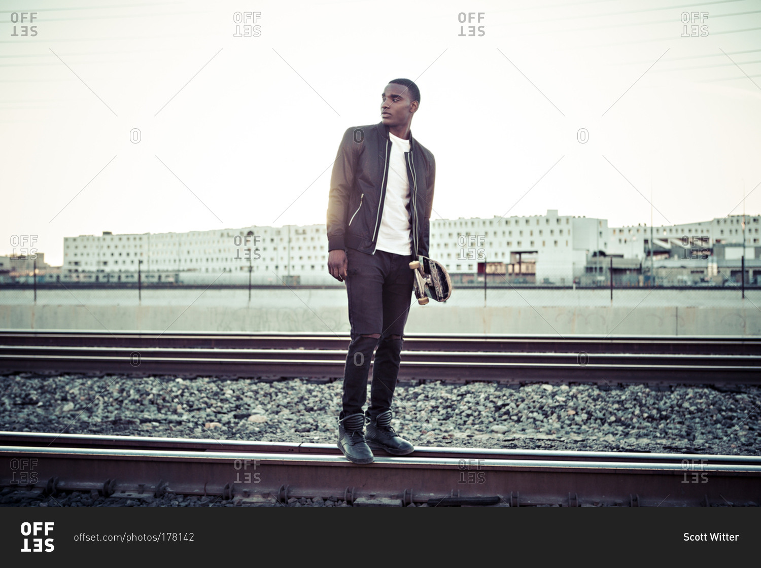 A skateboarder stands on train tracks