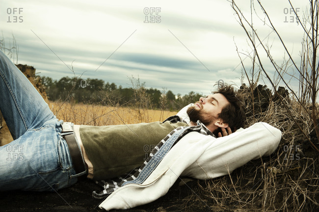 Man resting on log in a field