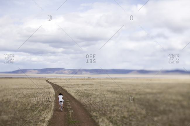 Woman riding a bike on a desolate dirt road