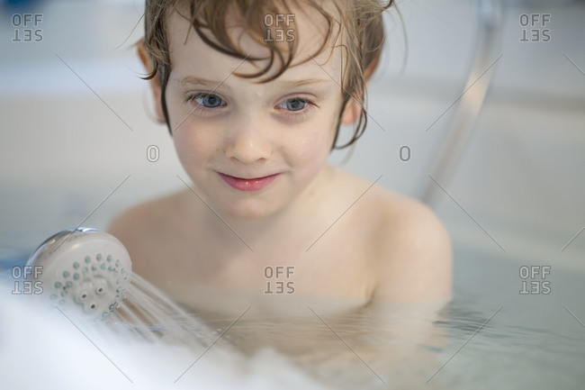 Boy playing with shower nozzle in the bathtub