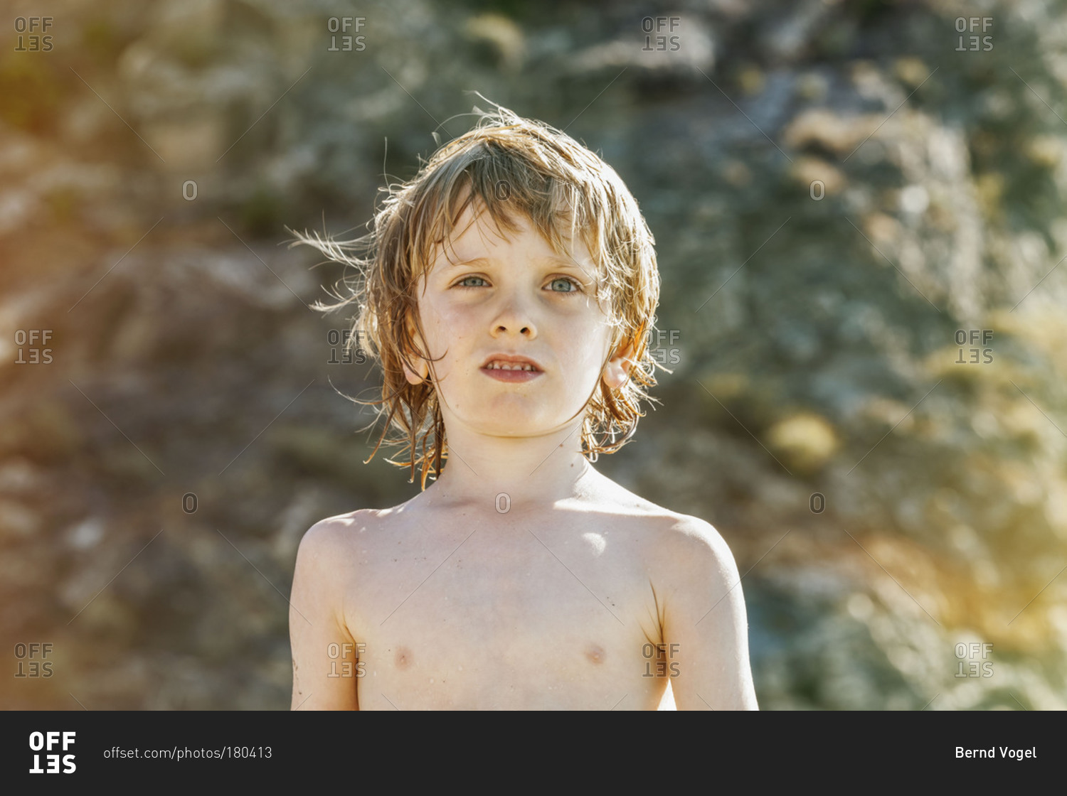 Portrait of a shirtless boy on beach stock photo - OFFSET