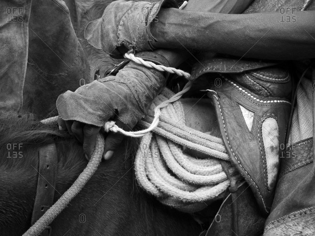 Close up of cowboy saddling horse