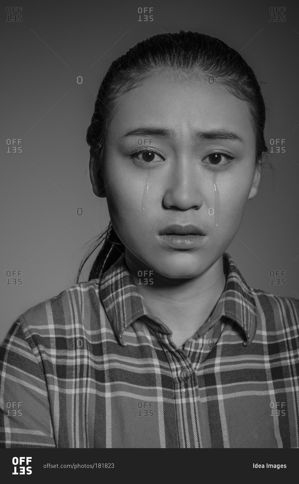 Studio shot of young Asian man crying