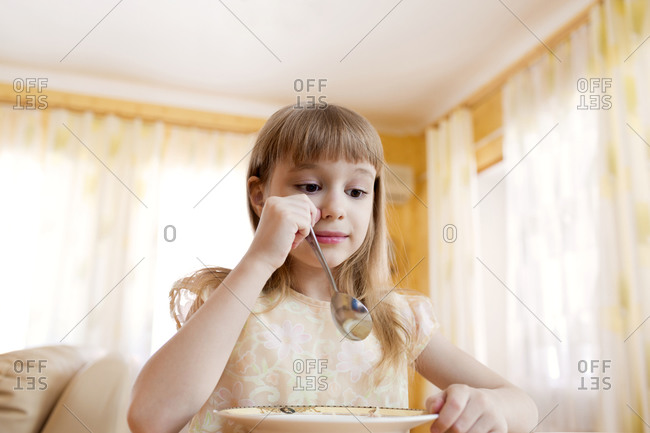A young girl eating soup