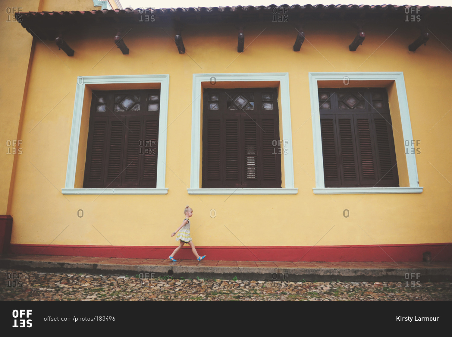 Girl passing typical colonial Cuban building, Trinidad, Cuba