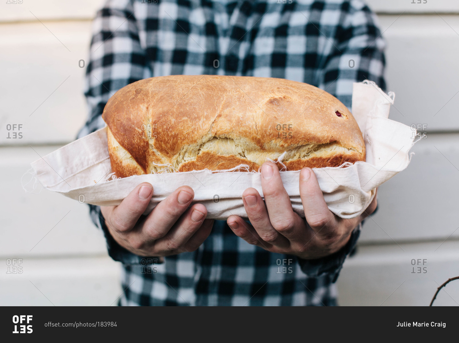 Man in checked shirt holding loaf of bread