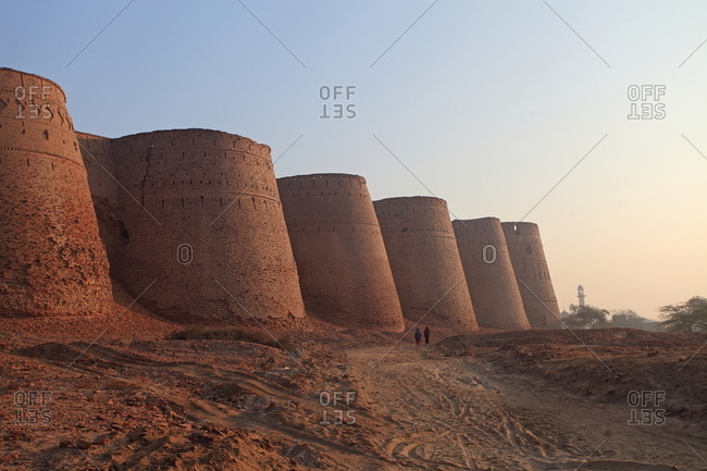 Bahawalpur, Pakistan - January 25, 2012: Two people walk down a path next to the Derawar Fort