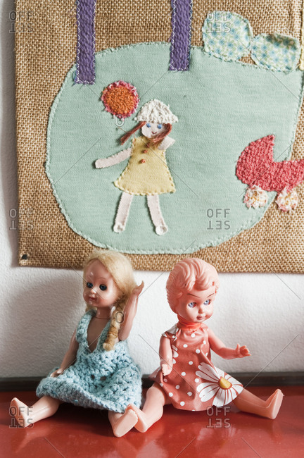 Plastic dolls beneath an embroidered picture