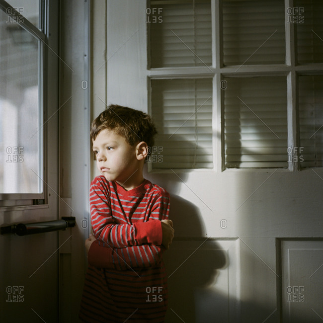Cold young boy staring out kitchen door