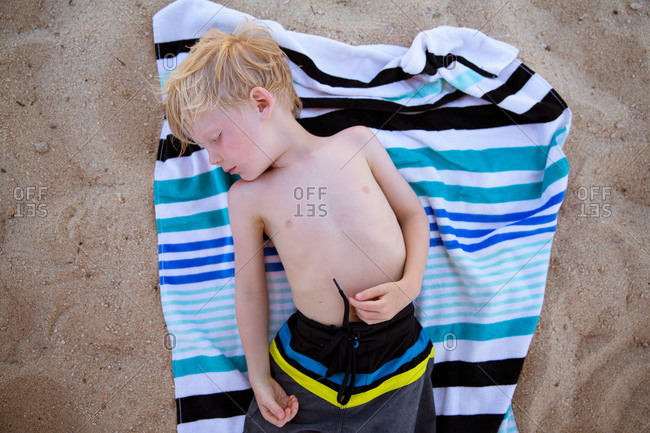 Top view of little boy napping on the beach