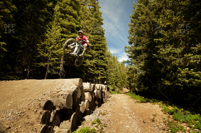 Man jumping over logs in a bike park
