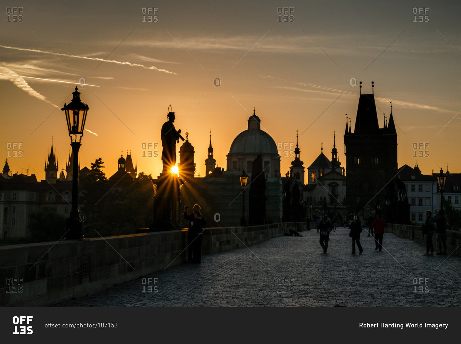 Starburst on silhouetted statue on Charles Bridge from low setting sun, Prague, Czech Republic