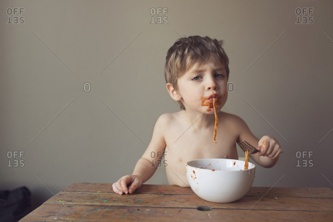 Messy boy eating pasta