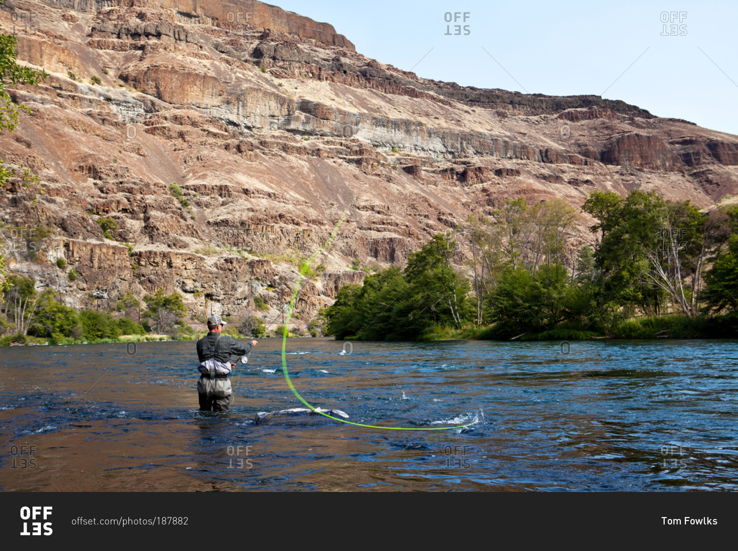 A man casts off in a canyon river